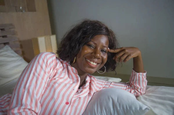 Jovem feliz e bonita negra afro-americana em pijama deitado relaxado e brincalhão na cama sorrindo alegre e positivo acordar de manhã otimista e fresco — Fotografia de Stock