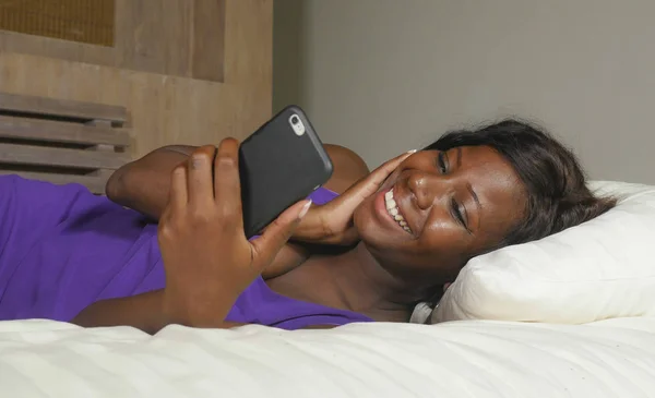 Hermosa y feliz negro mujer afroamericana tumbado relajado en la cama usando internet teléfono móvil sonriendo alegre creación de redes sociales de negocios o en línea citas — Foto de Stock