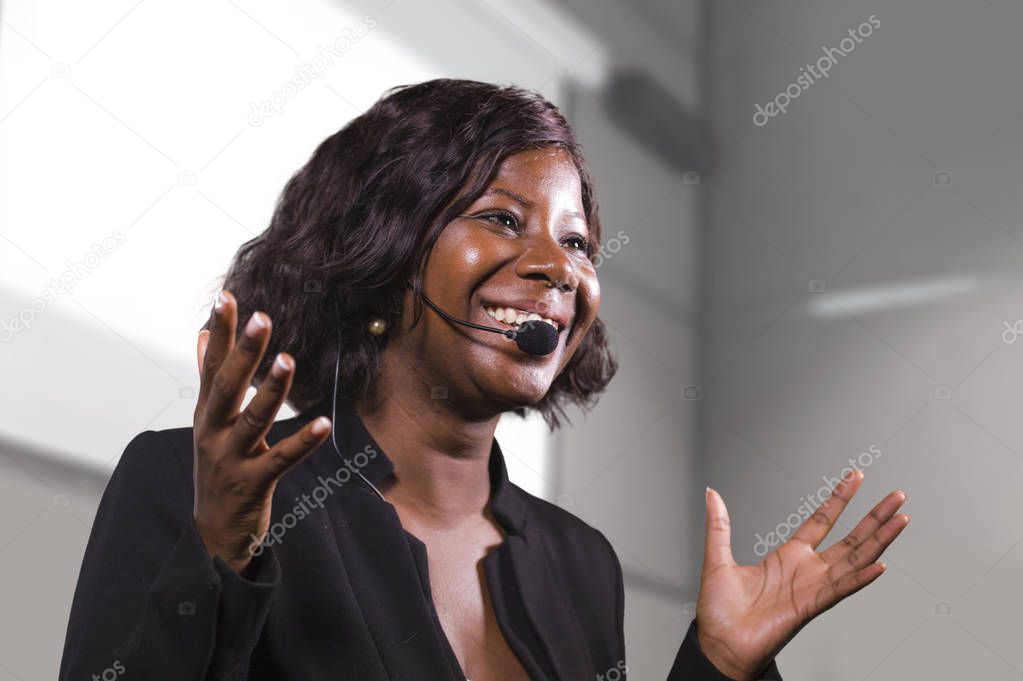 young attractive and confident black African American business woman with headset speaking in auditorium at corporate training event or seminar giving motivation conference