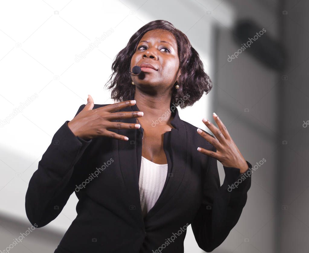 young attractive and confident black African American business woman with headset speaking in auditorium at corporate training event or seminar giving motivation conference