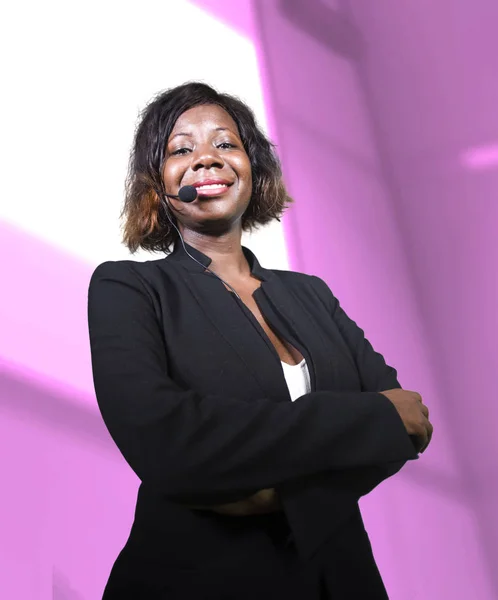 Успешная чернокожая афроамериканская деловая женщина с наушниками, выступающая в аудитории на корпоративном тренинге или семинаре, давая мотивацию и успех коучинга — стоковое фото