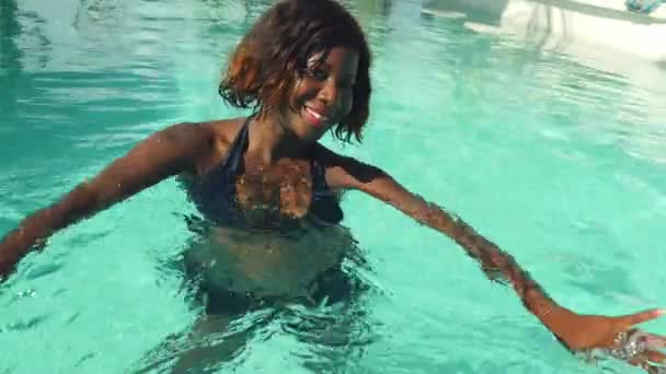幸せで 美しい黒いアフリカ系アメリカ人の若い女性ビキニ リラックスした熱帯のビーチ リゾートのプールで楽しさと遊び心のある笑みを浮かべて明るく楽しんで夏休日豪華な旅行を持っていること — ストック動画