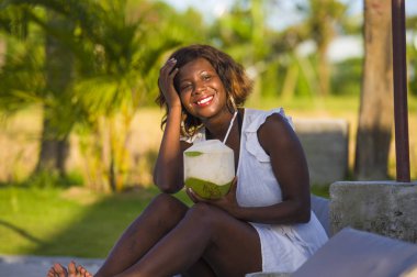 Yaz tatillerini rahat içme Hindistan cevizi suyu soğutma tropikal beach Resort havuz hamak yatan genç mutlu ve çekici siyah afro Amerikalı kadın