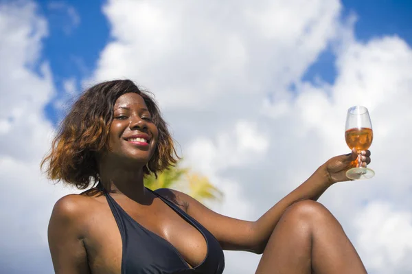 Ευτυχής και ελκυστικό μαύρο αφρικανική αμερικανική γυναίκα μπικίνι και καλοκαιρινό καπέλο, ένα ποτήρι κρασί στο luxury resort τροπική παραλία απολαμβάνοντας το ταξίδι διακοπές — Φωτογραφία Αρχείου