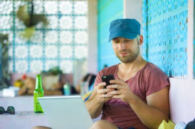 dizüstü bilgisayar ve cep telefonu açık havada ile çalışan mutlu ve kendine güvenen backpacker adam başarılı serbest girişimci ve internet iş dijital göçebe olarak rahat 