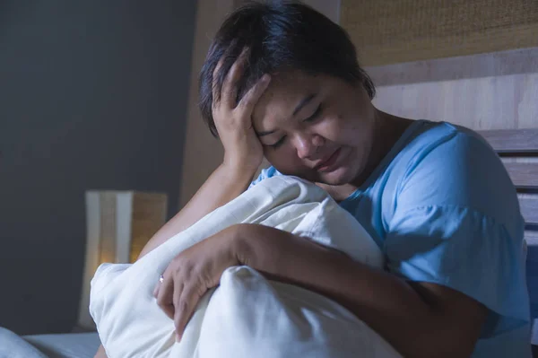 young sad and depressed fat and chubby Asian girl feeling upset and desperate crying on bed at home victim of bullying and discrimination for her plus size and overweight