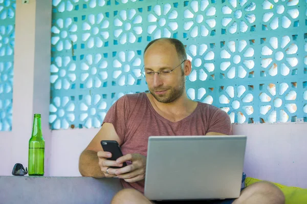 Hombre mochilero feliz y confiado que trabaja con el ordenador portátil y el teléfono móvil al aire libre relajado como empresario independiente acertado y nómada digital en trabajo del Internet — Foto de Stock