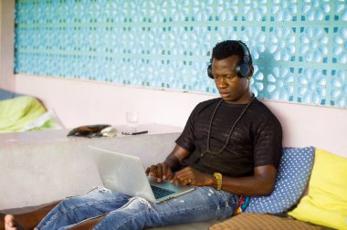 çekici ve hipster siyah African American iş adamı ağ dizüstü bilgisayar ve kulaklıklar konsantre ve düşünceli dijital göçebe internet iş