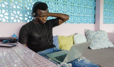 çekici ve hipster siyah African American iş adamı ağ dizüstü bilgisayar ve kulaklıklar konsantre ve düşünceli dijital göçebe internet iş