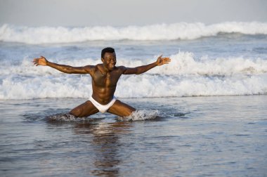 seksi kaslı vücut ve altı paketi ABS büyük deniz dalgaları ile sahilde ücretsiz silah açılış genç çekici ve uygun siyah Afrikalı Amerikalı adam sanatsal portre