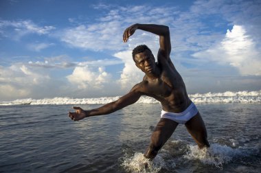 genç çekici ve uygun siyah African American Man güçlü kaslı vücut yaz mavi gökyüzü üzerinde izole sahilde serin model tutum poz ile portre