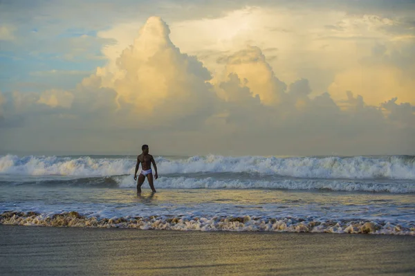 Művészi portréja fiatal vonzó és illeszkedés fekete afro-amerikai férfi, szexi izmos test gondtalan élvező természet érzés ingyenes strandon a vadon élő tenger nagy hullámok — Stock Fotó