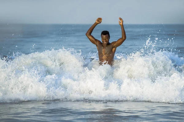 Retrato de playa de joven en forma y atractivo negro hombre afroamericano con musculoso hermoso cuerpo disfrutando juguetón en el mar jugando en el agua divirtiéndose — Foto de Stock