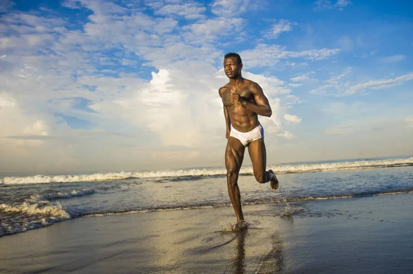 Happy and attractive black African American man with fit healthy and muscular body running on beach sea water having fun enjoying Summer holidays feeling free — Stock Photo, Image