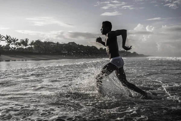 Happy and attractive black afro American man with fit healthy and muscular body running on beach sea water having fun enjoying Summer holidays feeling free — Stock Photo, Image