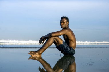 genç çekici ve rahat siyah Afro Amerikan adam uygun vücut ve kas arka sahilde oturan güzel görünüm düşünme ve meditasyon ücretsiz zevk