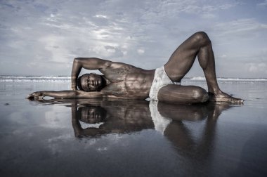 genç çekici ve seksi siyah Afro Amerikan adam atletik kas vücudu ile erkek güzellik ve plastisite kavramı çöl plajında deniz suyunda serin poz