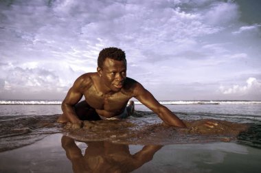 genç çekici ve seksi siyah Afro Amerikan adam atletik kas vücudu ile erkek güzellik ve plastisite kavramı çöl plajında deniz suyunda serin poz