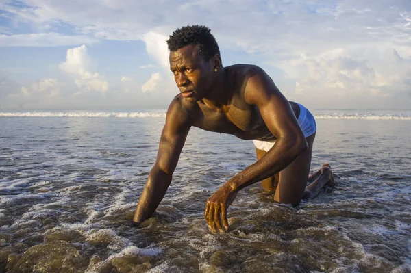 Joven atractivo y sexy negro afro americano hombre con atlético muscular cuerpo posando fresco en agua de mar en desierto playa en masculino belleza y plasticidad concepto — Foto de Stock