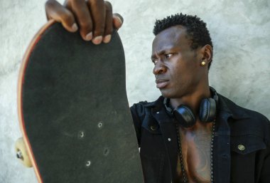 genç çekici ve kendine güvenen hipster siyah Afro Amerikan adam sokak duvarında şehir tarzında badass adam olarak paten tahtasında eğilme serin izole portre