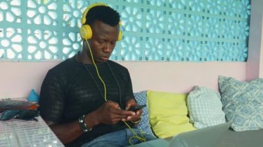 Genç serin ve çekici siyah Afro Amerikan hipster adam kulaklık ağ cep telefonu ve dizüstü bilgisayar ile dijital göçebe iş ve internet iş yaşam tarzı ile rahat