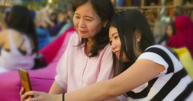 sahilde genç mutlu ve güzel Asya Çinli kız annesi ile selfie fotoğraf çekerken, bir 60s Olgun kadın, yaz tatilleri birlikte seyahat zevk