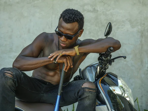 Estilo de vida urbano retrato de cuerpo en forma y aspecto peligroso negro hombre afroamericano con el torso desnudo y gafas de sol sentado en scooter con bate de béisbol — Foto de Stock