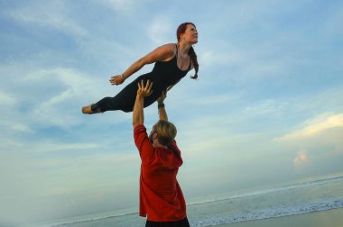 Genç, çekici ve güzel akrobat çift akroyoga egzersizi yapıyorlar. Dengeli bir şekilde yoga yapıyorlar. Rahatlama ve meditasyon konseptiyle.
