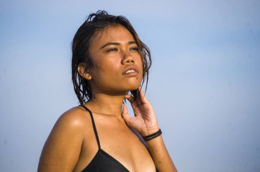 Genç, güzel ve seksi bikinili, ıslak saçlı, tropikal sahilde tatilin tadını çıkaran egzotik güzellik konseptiyle denizde rahat ve mutlu pozlar veren Asyalı bir kız.
