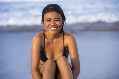 Genç, egzotik ve çekici bikinili gülümseyen, rahat ve kaygısız bir Asyalı kız tropik sahilde mutlu ve neşeli tatiller geçiriyor ve denizde eğleniyor.