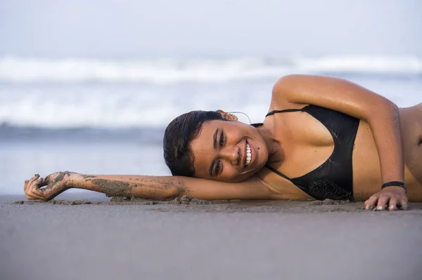 Junge schöne und glückliche asiatische Frau im Bikini liegt nass am Sandstrand und spielt fröhlich lächelnd mit Meerwasser in exotischer Inselschönheit — Stockfoto