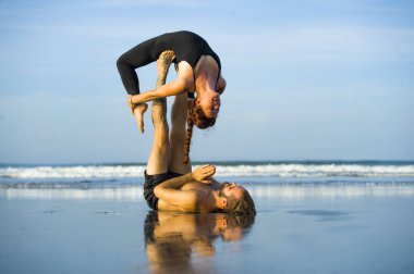 Genç, çekici ve güzel akrobat çift akroyoga egzersizi yapıyorlar. Dengeli bir şekilde yoga yapıyorlar. Rahatlama ve meditasyon konseptiyle.