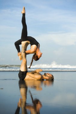 Genç, çekici ve güzel akrobat çift akroyoga egzersizi yapıyorlar. Dengeli bir şekilde yoga yapıyorlar. Rahatlama ve meditasyon konseptiyle.