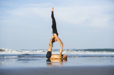 Genç, çekici ve güzel akrobat çift akroyoga egzersizi yapıyorlar. Dengeli bir şekilde yoga yapıyorlar. Rahatlama ve meditasyon konseptiyle.