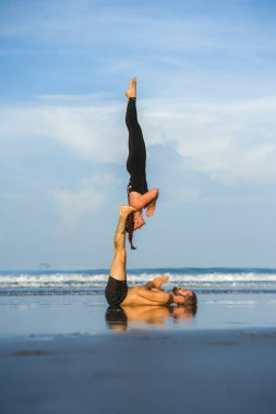 Genç, çekici ve güzel akrobat çift akroyoga egzersizi yapıyorlar. Dengeli bir şekilde yoga yapıyorlar. Rahatlama ve meditasyon konseptiyle.