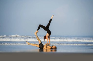 Genç, çekici ve güzel akrobat çift akroyoga egzersizi yapıyorlar. Dengeli bir şekilde yoga yapıyorlar. Rahatlama ve meditasyon konseptiyle.