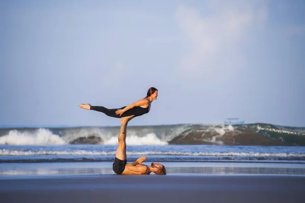 Genç, çekici ve güzel akrobat çift akroyoga egzersizi yapıyorlar. Dengeli bir şekilde yoga yapıyorlar. Rahatlama ve meditasyon konseptiyle. — Stok fotoğraf