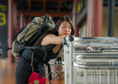 Havaalanı terminalindeki stresli ve bitkin Asyalı Japon kadın yorgun ve endişeli hissediyor. Bağlantı uçuşunu kaçırıyor veya tatilde gecikme yaşıyor. 