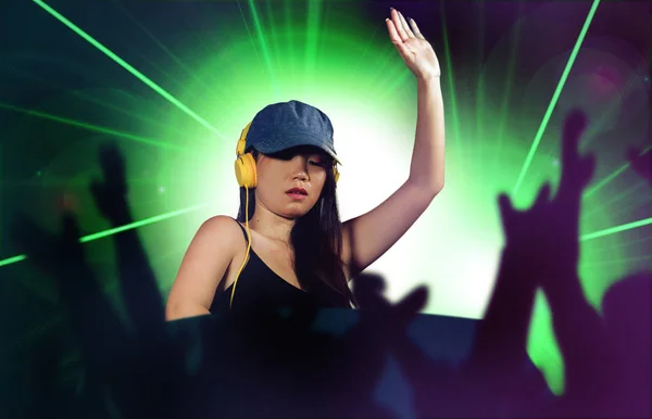 young attractive and happy Asian Korean DJ woman remixing techno music using deejay gear and headphones at night club with lights background in clubbing fun at night
