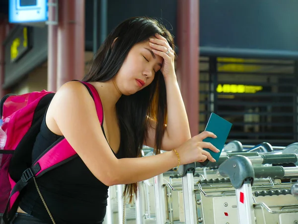 Молодая напряженная и измученная азиатская китаянка на терминале аэропорта чувствует себя уставшей и обеспокоенной отсутствием стыковочного рейса или задержкой в праздничных поездках — стоковое фото