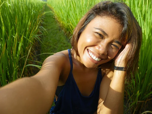 若い幸せとエキゾチックな島のアジアの女の子インドネシアから携帯電話で自撮り自画像写真を撮る陽気で興奮したポーズ田んぼの自然背景 — ストック写真