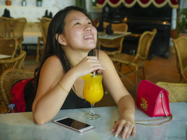 若い幸せとリラックスしたアジアの中国人観光客の女性は、ホテルのカフェやレストランリゾートで健康的なオーランスジュースを飲んで観光旅行やライフスタイルで笑顔 — ストック写真