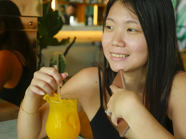 Joven feliz y relajado asiático chino turista mujer beber sano orance jugo en hotel café o restaurante resort sonriendo alegre en turismo viaje y estilo de vida —  Fotos de Stock