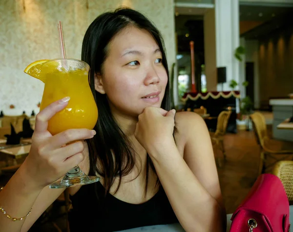 Joven feliz y relajado asiático coreano turista mujer beber sano orance jugo en hotel café o restaurante resort sonriendo alegre en turismo viaje y estilo de vida —  Fotos de Stock