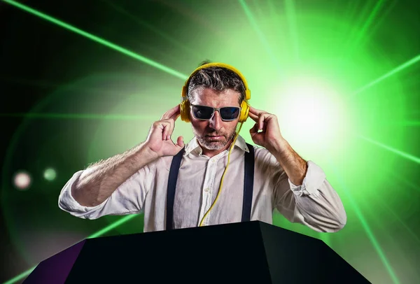 Junge attraktive und coole DJ in Hemd und Hosenträgern Remixing Musik in einem Nachtclub mit Kopfhörern in Party-Strobo und Laserlicht Hintergrund in Clubbing und Nachtleben — Stockfoto