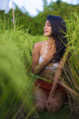 Genç, mutlu ve güzel Latin kadın neşe içinde gülüyor. Asya 'da yeşil pirinç tarlasında izole edilmiş seksi poz veriyor. Turizm, yaz tatili ve turizm konsepti.