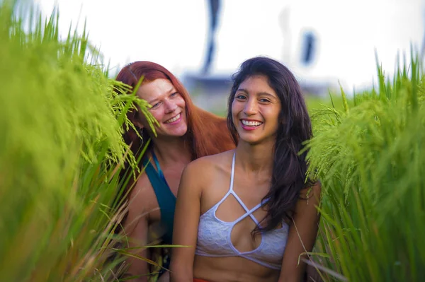 latin woman and her attractive red hair girlfriend both girls enjoying Summer holidays together on rice field smiling happy relaxed in diversity ethnicity friendship