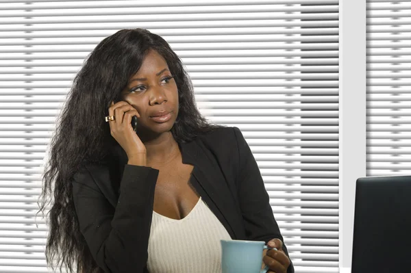 Jeune belle et occupée femme d'affaires afro-américaine noire parlant sur téléphone mobile au bureau travaillant avec ordinateur portable boire du café dans la réussite professionnelle de la femme — Photo