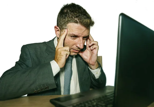 Jovem estressado empresário em terno e gravata trabalhando oprimido no escritório laptop mesa de computador sofrendo dor de cabeça causa de estresse no trabalho isolado — Fotografia de Stock