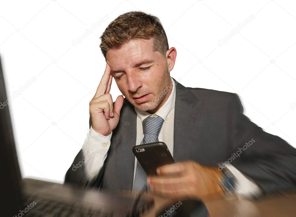 young stressed businessman in suit and tie working overwhelmed at office laptop computer desk suffering headache cause of work stress isolated